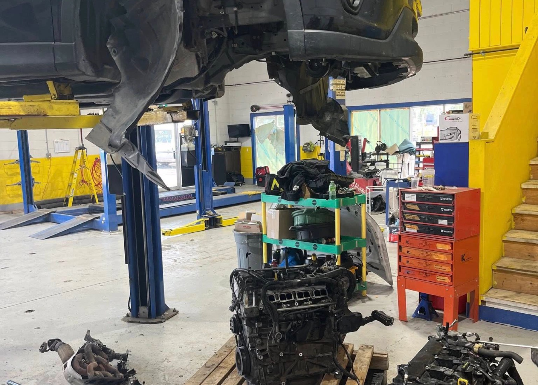 Inside the Newstead Mechanical bay: blue two-post lifts, yellow arms, engines on pallets, work in progress.
